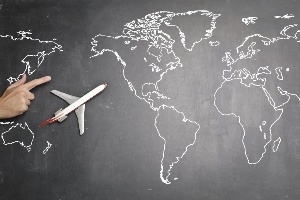 World map on blackboard with a toy airplane showing global travel routes and trip planning